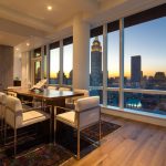 Modern apartment dining room with wall of windows and city views.