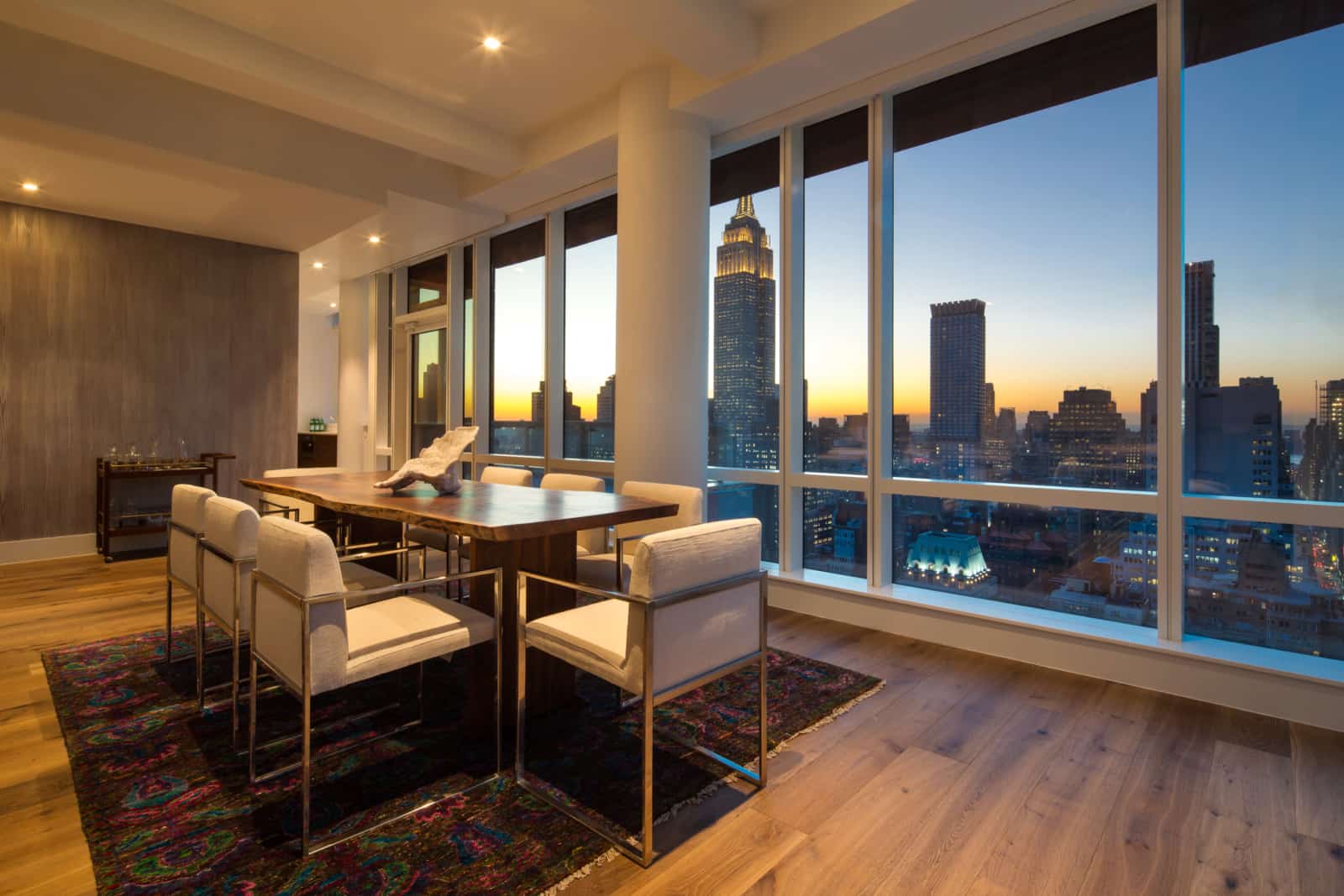 Modern apartment dining room with wall of windows and city views.