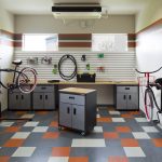 Interior of a bike repair room with workbench, tool cabinets, various tools and two bikes on stands.