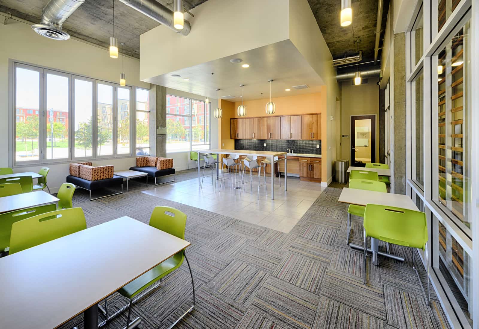 Common room with tables and chairs and a kitchen on the back wall.