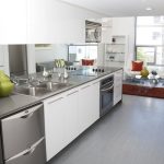Interior of modern kitchen with stainless steel appliances and sitting area in the background.