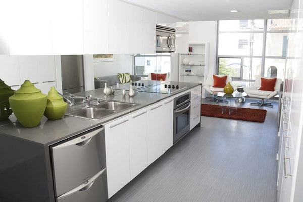 Interior of modern kitchen with stainless steel appliances and sitting area in the background.