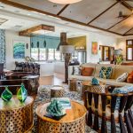 Interior of common area with couches, Polynesian furniture, and kitchen area in background.