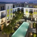 View of the courtyard pool surrounded by palm trees at night from an elevated angle.