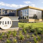 Exterior with sign for Pearl apartments with buildings in the background