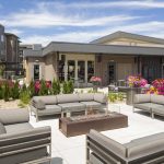 Exterior of glass-walled fire pit and couches with apartment buildings in the background