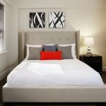 Interior of apartment bedroom with an upholstered bed, side table and lamp.