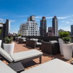 Exterior of outdoor courtyard with lounge chairs, side tables and views of the city.