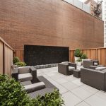 Exterior of outdoor courtyard with modern chairs, tables and a water feature in the background..