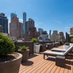 Exterior of roofdeck with lounge chairs, planters and a view of the city in the background.