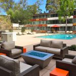 Exterior of pool deck with modern outdoor couches with fire pit in the foreground.