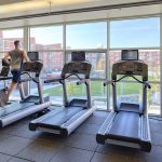 Treadmills in front of large windows with views of other apartment buildings across the way.