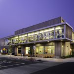 Exterior of modern building with a view of the fitness center on the second floor.