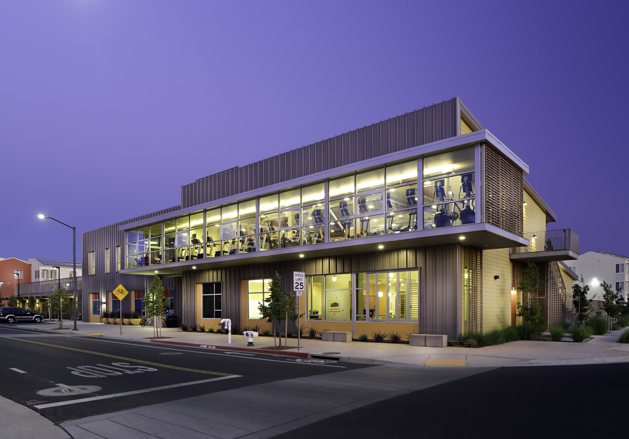 Exterior of modern building with a view of the fitness center on the second floor.