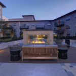 Exterior of courtyard with couches and fireplace surrounded by 3- and 4-story apartment building