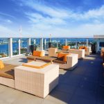 Roof deck with lounge chairs with a view of the water in the background.