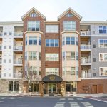 Exterior street-level view of apartment complex entrance with road in foreground
