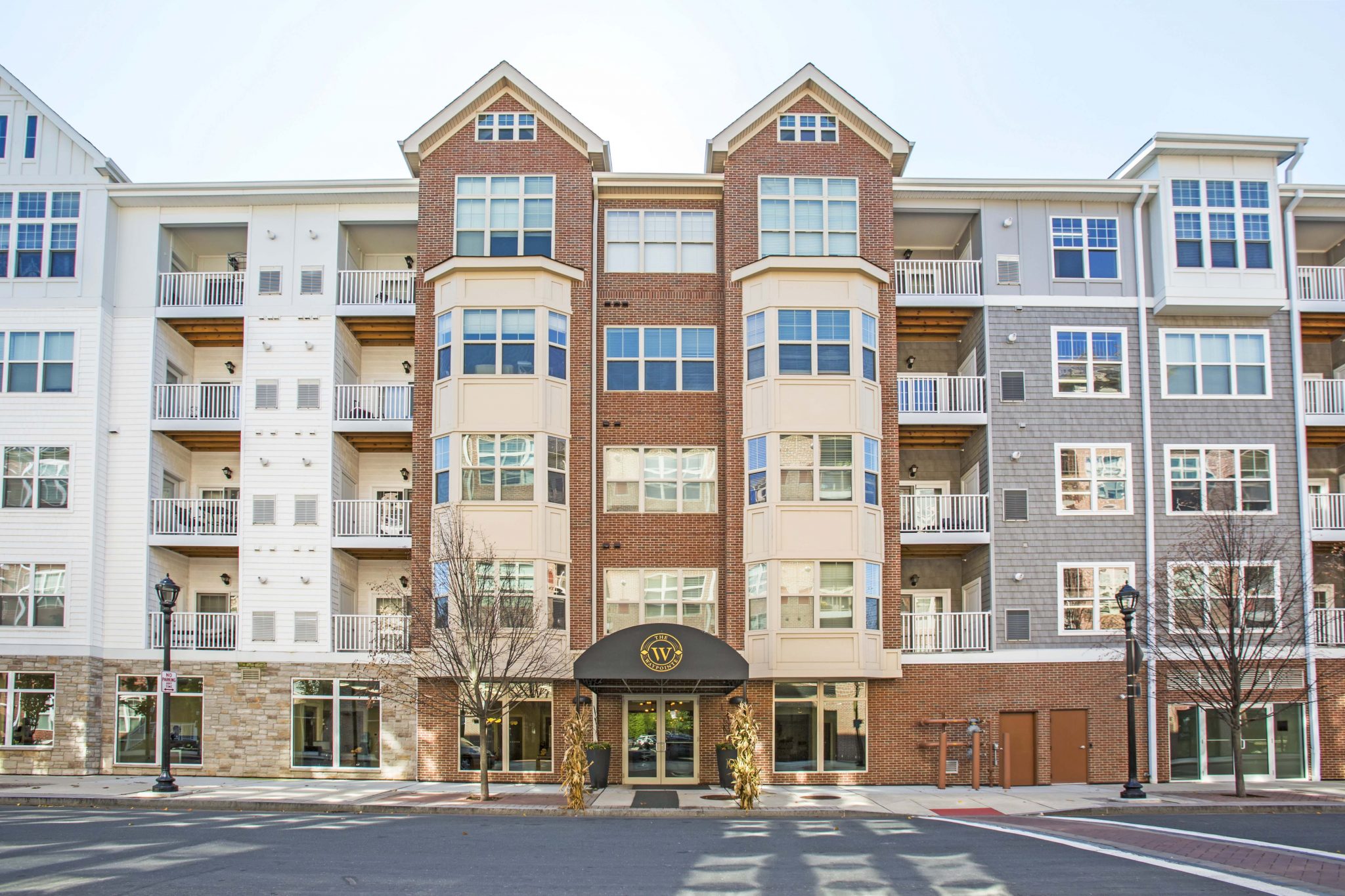 Exterior street-level view of apartment complex entrance with road in foreground