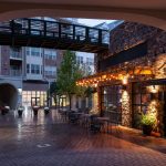 Exterior of courtyard with restaurant, fountain, and overhead walkway with apartment building in background