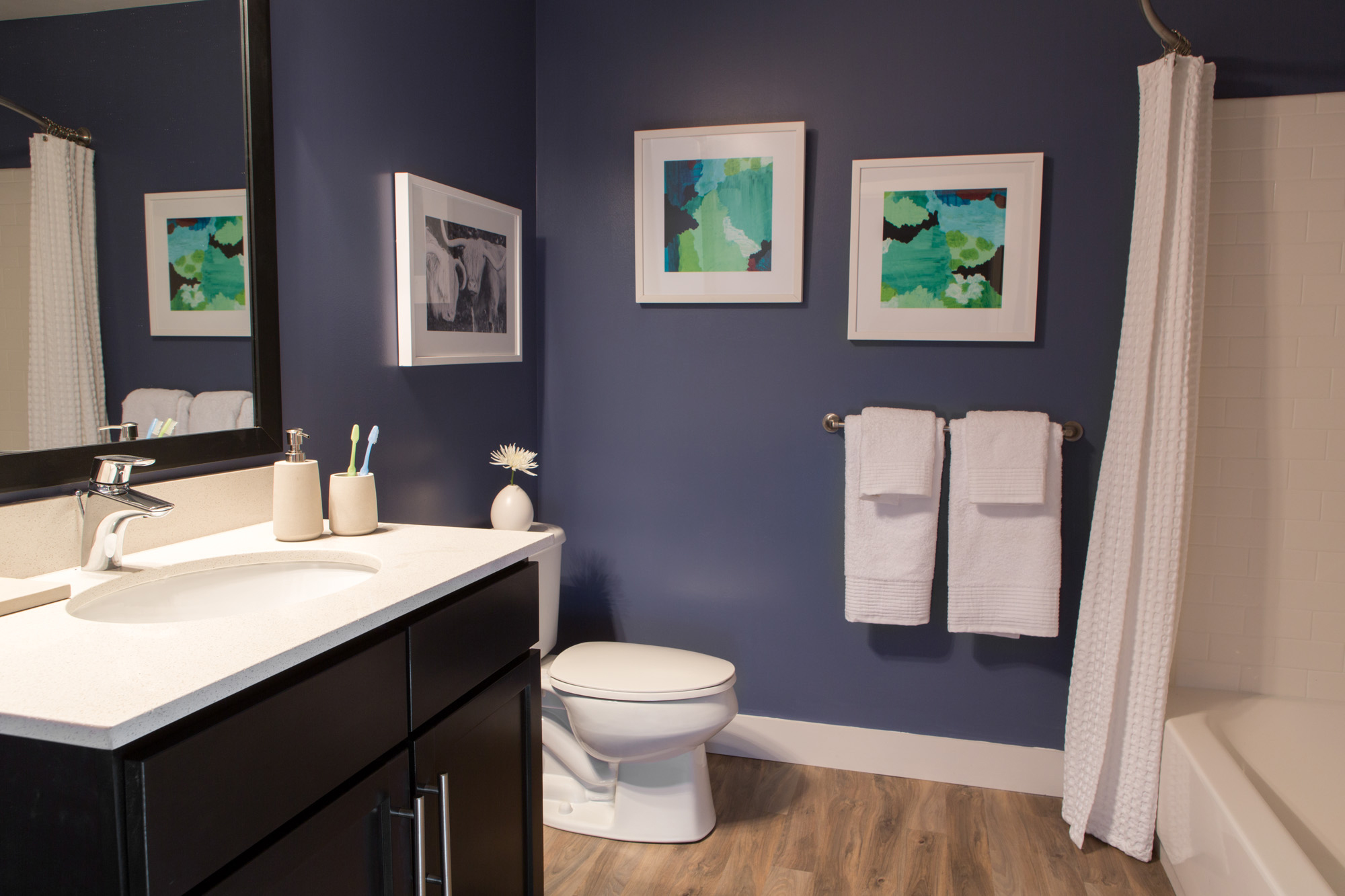 Interior of apartment bathroom with vanity, toilet and tub shower.