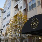 Exterior of apartment complex with awning over entranceway in foreground