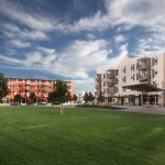 Exterior of several 4 story apartment buildings with a lawn in the foreground.