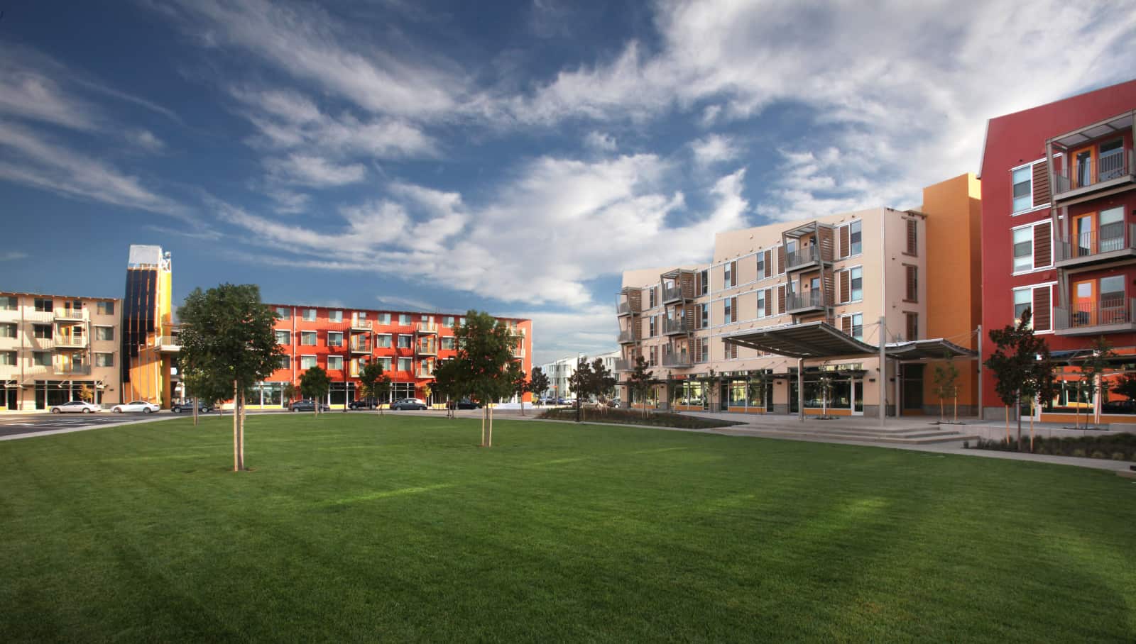 Exterior of several 4 story apartment buildings with a lawn in the foreground.