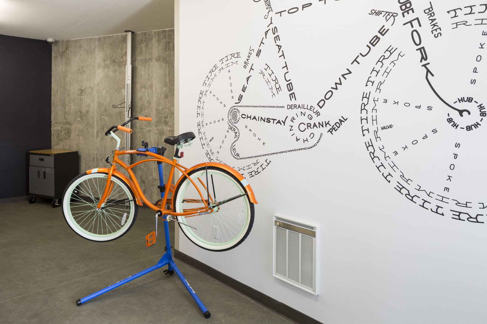 Interior with beach cruiser bicycle on work stand with bike graphic on wall behind it.