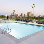 Rooftop pool surrounded by seating with downtown skyline in background.