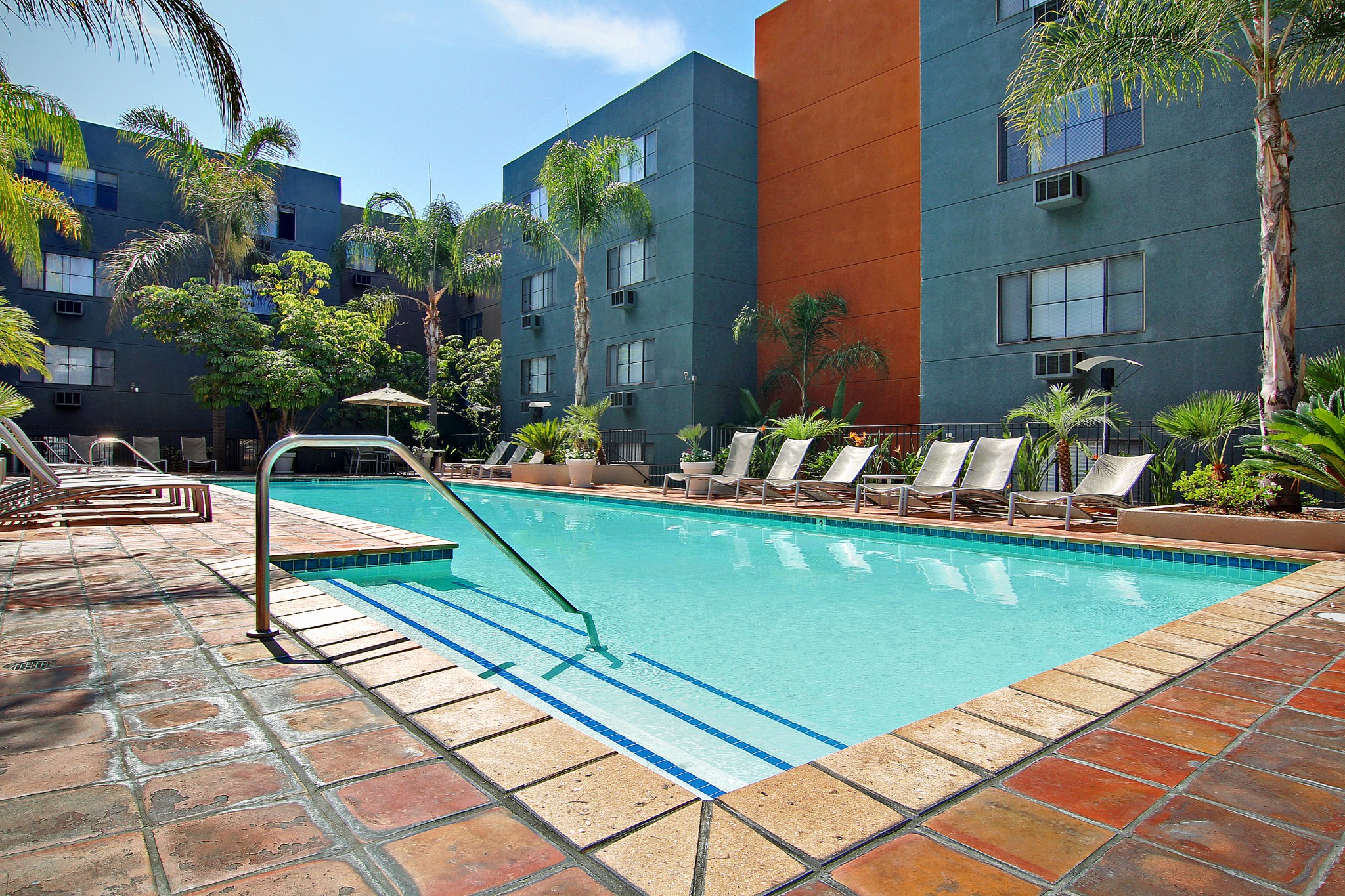View of courtyard pool with lounge chairs, trees, and building in the background..
