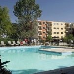 View of the pool in the foreground and apartment building in the background.
