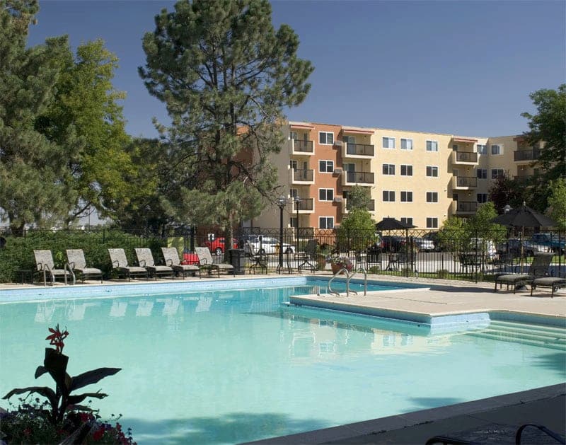 View of the pool in the foreground and apartment building in the background.