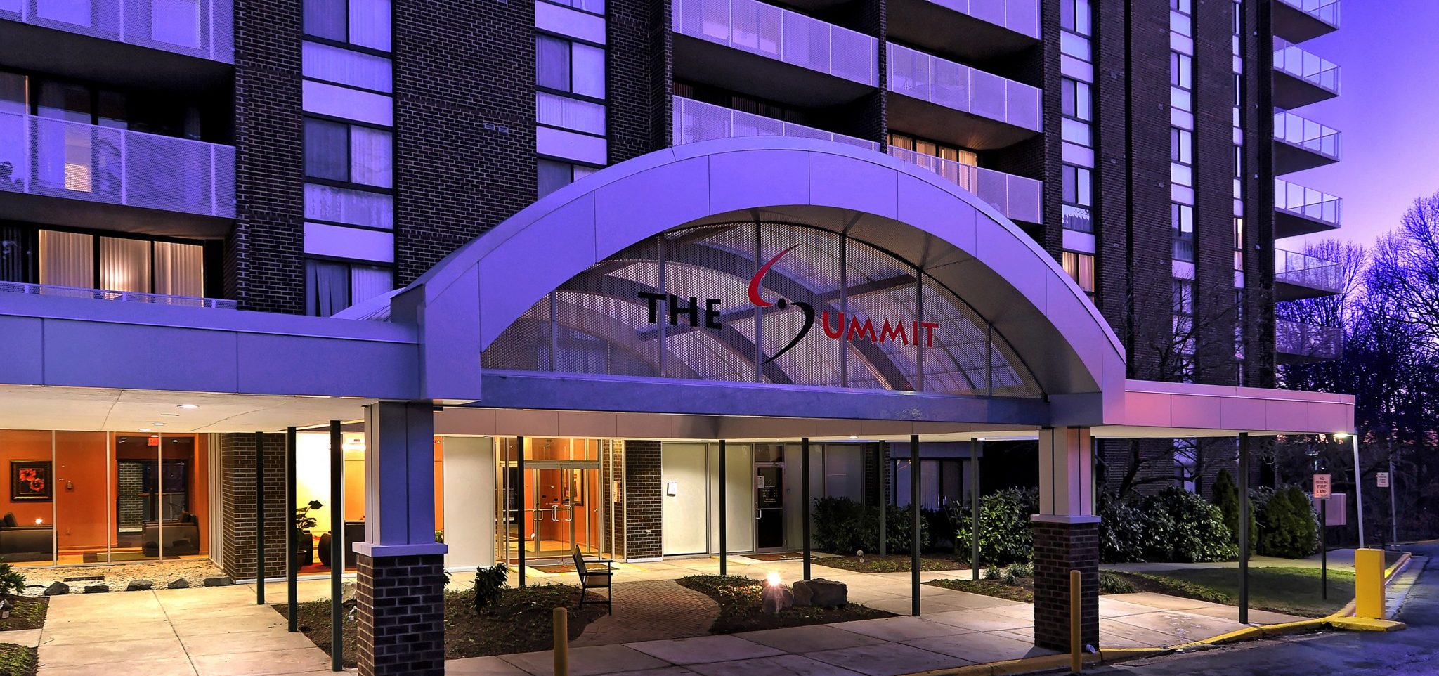 The sunset casts a purple glow on the entrance of the building.