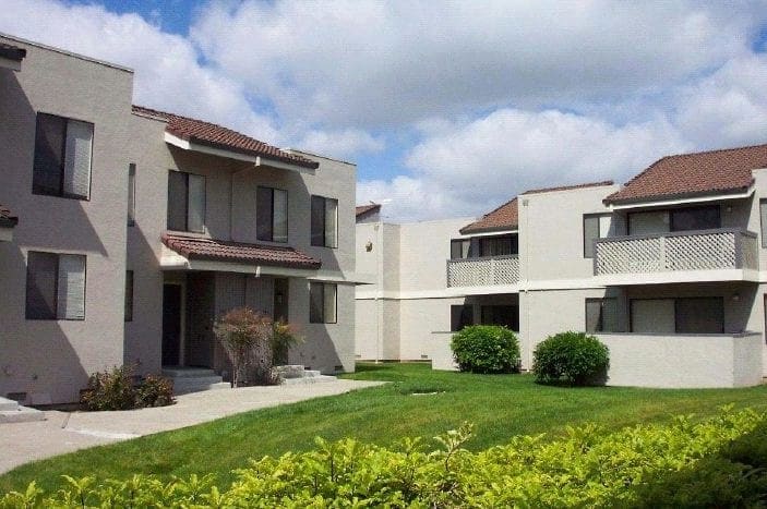 Exterior view of 2 story building with balconies and entrances to units.