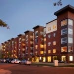 Exterior of apartment building from across the street at twilight.