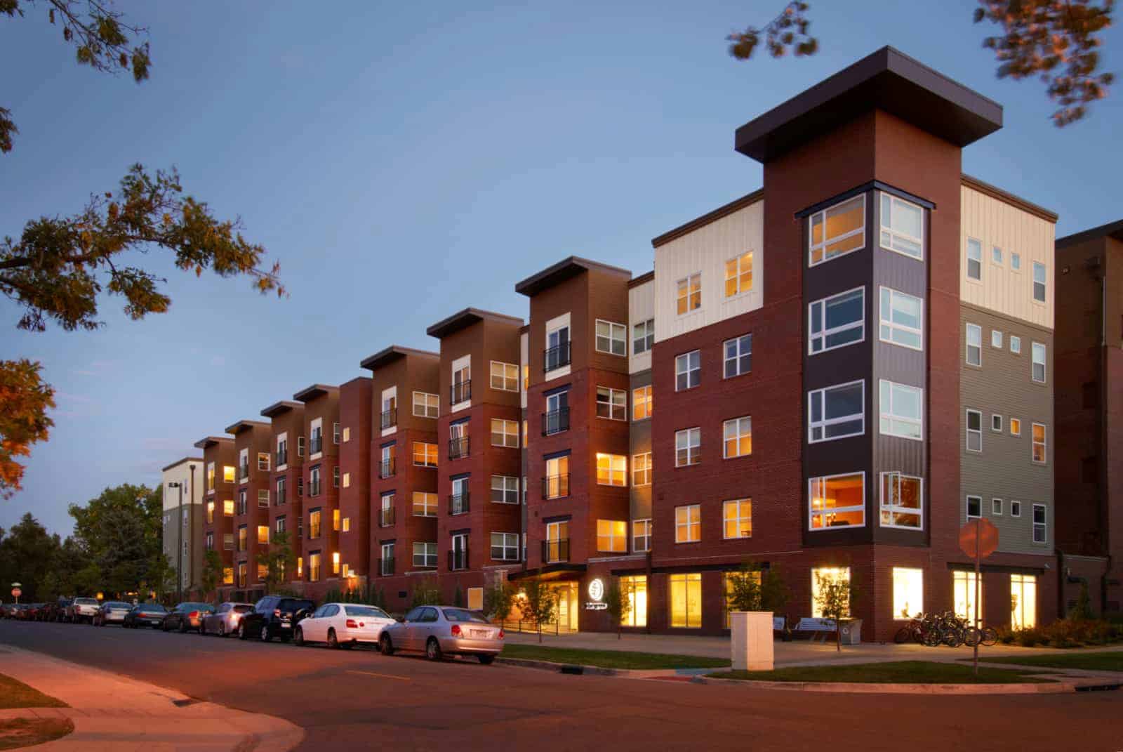 Exterior of apartment building from across the street at twilight.
