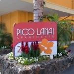 Pico Lanai apartment signage amongst flowers and palms.