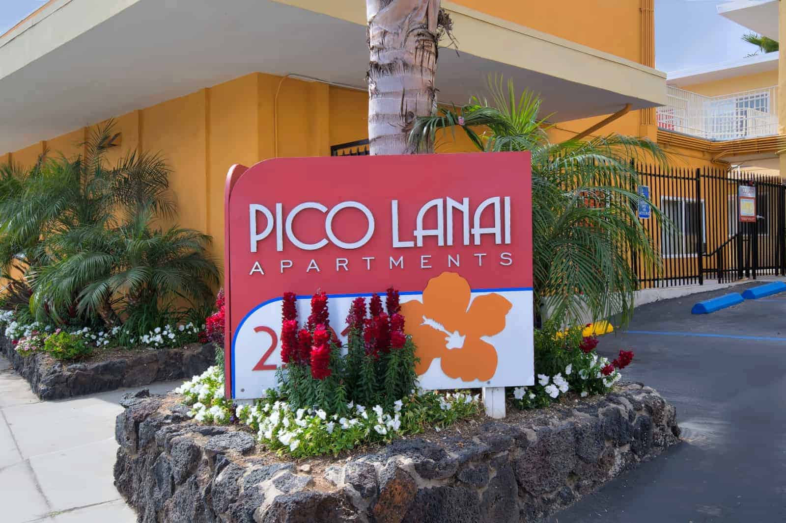 Pico Lanai apartment signage amongst flowers and palms.