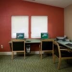 View of 3 computer stations and a printer in a business center.
