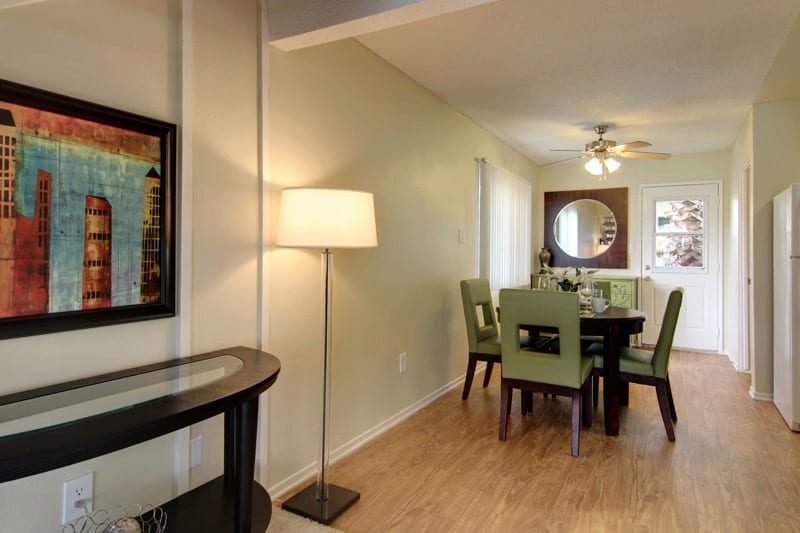 Interior view of dining area with round table and four chairs, fan above and lamp and console in the foreground.