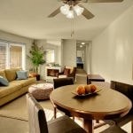 Interior of apartment living and dining room area with couch, chairs and table.