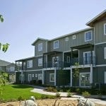 Exterior of 3 story apartment building with a lawn and landscaping in the foreground.