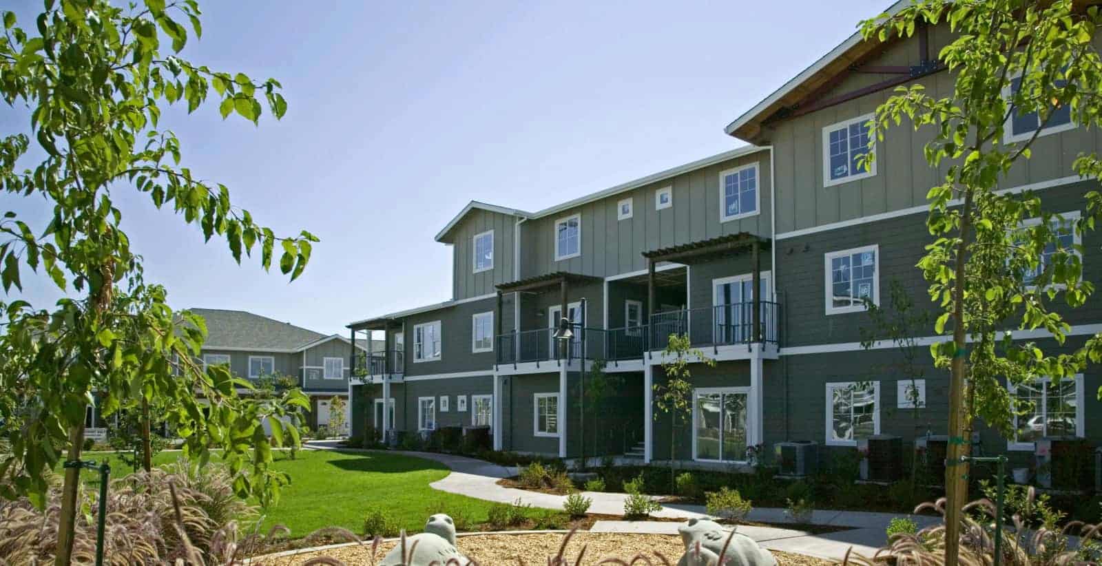 Exterior of 3 story apartment building with a lawn and landscaping in the foreground.