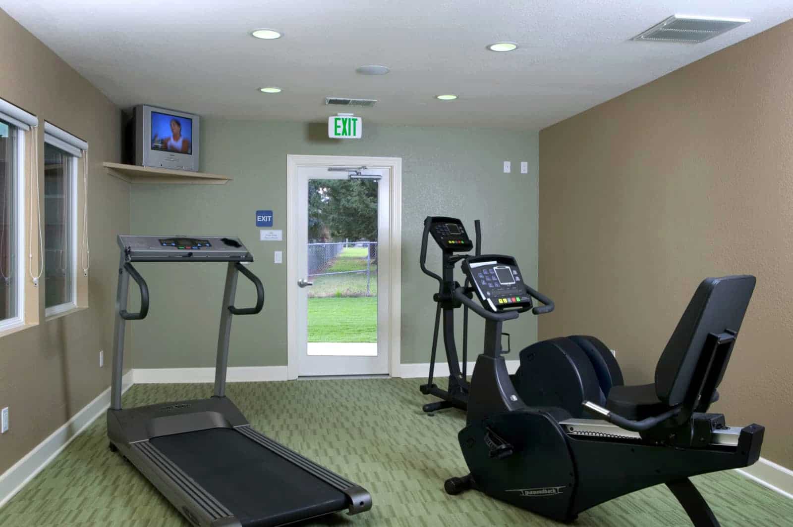 View of the fitness center with 3 cardio machines and a TV.