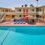 View of the pool surrounded by a white fence and the apartment building in the background.