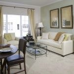 Interior of apartment living room with couch, chair, coffee table and dining set in the foreground.