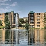 View of the lake and fountain with 5 story apartment buildings in the background.