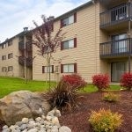 Exterior of 3 story apartment building with balconies and landscaping in the foreground.