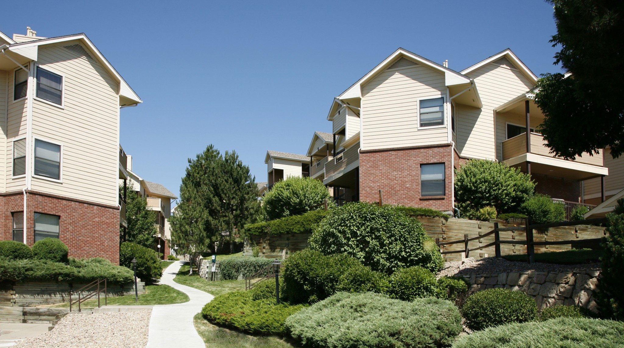 View of a walkway flanked by landscaping between buildings.