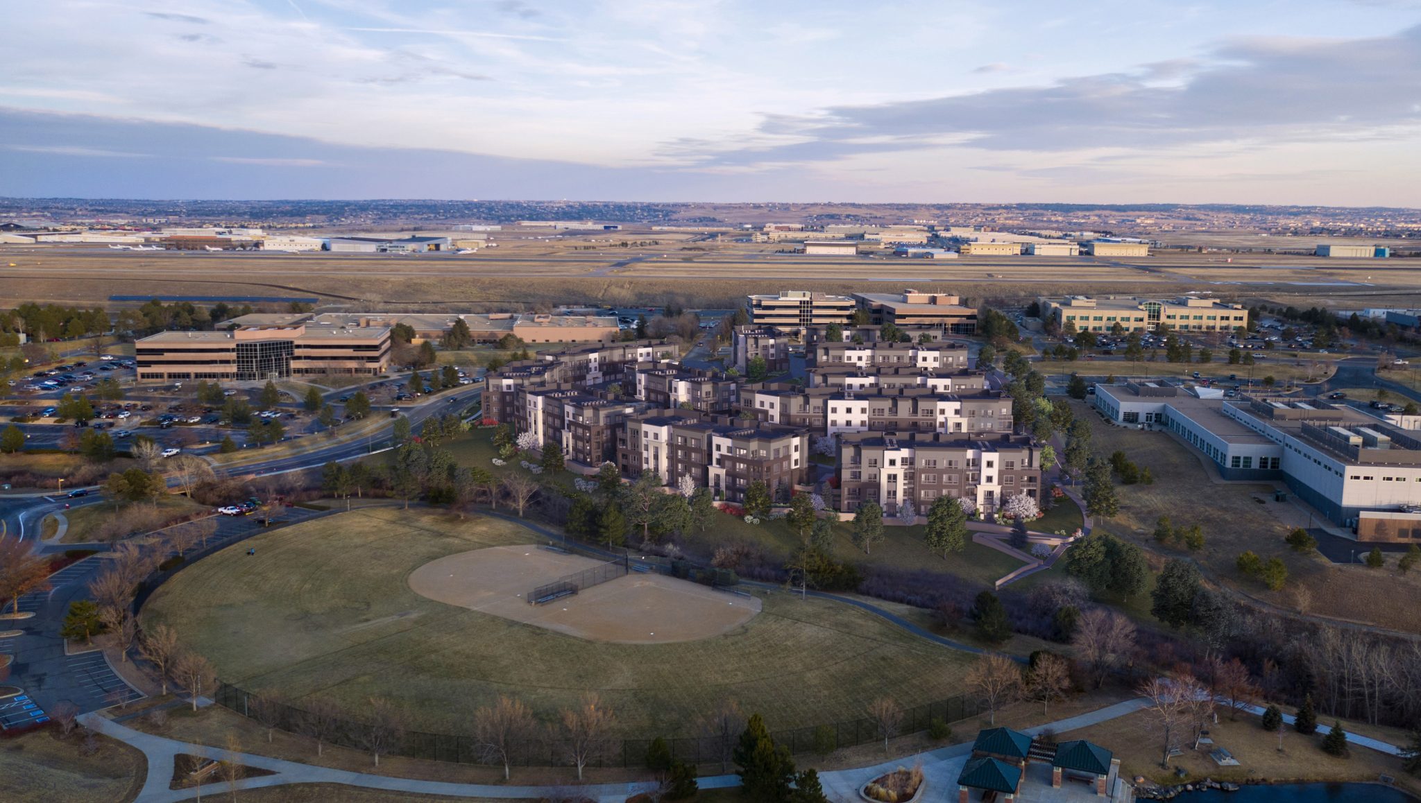 Aerial exterior of entire apartment complex with baseball fields in the foreground and horizon in background